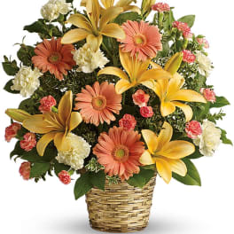 Basket arrangement of yellow lilies, peach gerberas, and white carnations