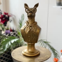 Gold animal bust sculpture wearing glasses on a round table