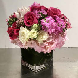 Pink and white rose bouquet in a square glass vase