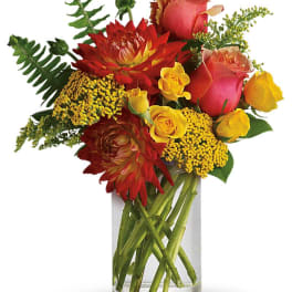 Bouquet of red, pink, and yellow flowers in a clear glass vase