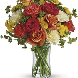 Bouquet of red, orange, and white roses in a clear glass vase
