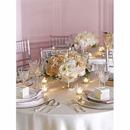 Round centerpiece of cream and peach roses on a banquet table