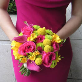 Woman holding a bright pink bouquet with roses, calla lilies, and yellow flowers