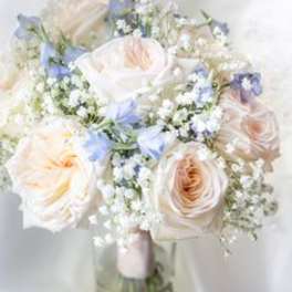 Blush and white rose bouquet in a glass vase with small blue flowers