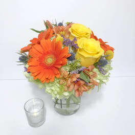 Bouquet of orange gerbera daisies and yellow roses in a glass vase