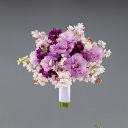 Lavender and pink bridal bouquet with small blossoms on a gray background