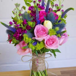 Bouquet of pink roses and purple flowers wrapped with twine