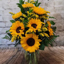 Sunflower bouquet in a clear glass vase with yellow filler flowers