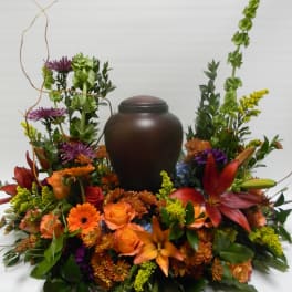 Orange and purple floral arrangement around a dark urn