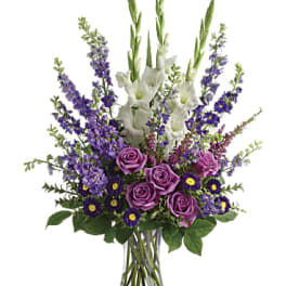 Purple roses and white gladiolus in a clear glass vase
