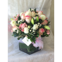 Pink and white bouquet in a square glass vase with a pink ribbon