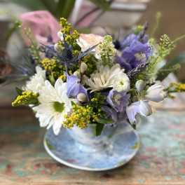 Pastel bouquet of white daisies and lavender blooms in a glass vase