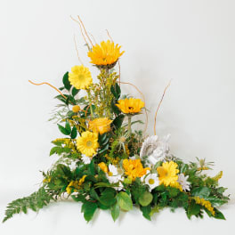 Yellow and white floral arrangement with a small angel figurine