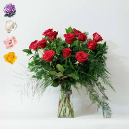 Red roses arranged in a clear glass vase with airy greenery