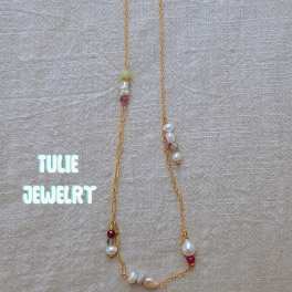 Gold necklace with pearl and bead accents on beige fabric