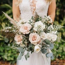 Bride holding a bouquet of blush and white roses with greenery