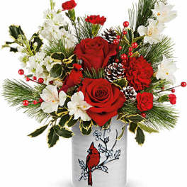 Red roses and white flowers in a decorative vase with pine accents