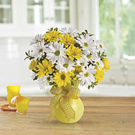 Yellow and white daisy bouquet in a yellow vase with a gingham ribbon