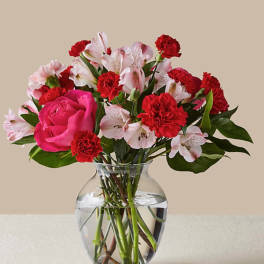 Pink rose and red carnation bouquet in a clear glass vase