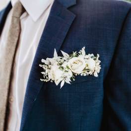 White floral boutonniere pinned to a navy suit jacket