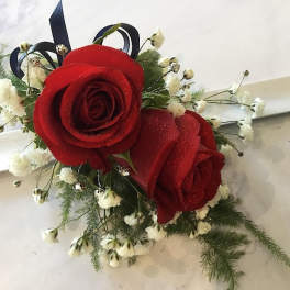 Red rose corsage with white baby's breath on a white ribbon