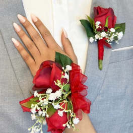 Red rose boutonniere and wrist corsage on a gray suit