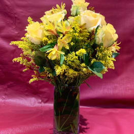 Yellow roses and alstroemeria in a clear glass vase