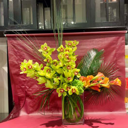 Bright orchid and calla lily arrangement in a clear square vase