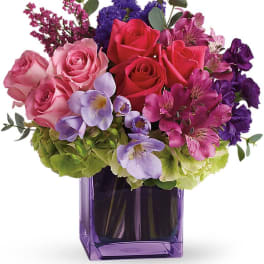Pink and purple mixed bouquet in a purple glass vase