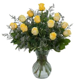 Long stemmed yellow roses, vased with a variety of greenery and filler