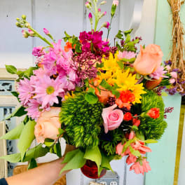 Mixed bouquet of pink, peach, and yellow flowers in a red vase