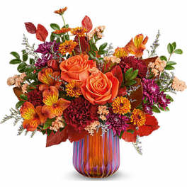 Orange roses and mixed autumn flowers in a striped glass vase