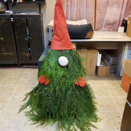A gnome-shaped decoration made of greenery with a red hat and white nose