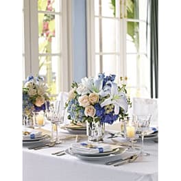Blue and white floral centerpiece in a glass vase on a set dining table