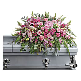 Pink and white floral casket spray on a silver casket