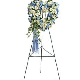 Heart-shaped floral wreath on a stand with blue and white flowers
