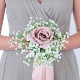 Bridesmaid holding a pink rose wrist corsage with baby's breath and ribbon
