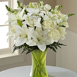 White lilies and roses in a green glass vase
