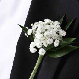 White boutonniere with small clustered flowers and dark green leaves