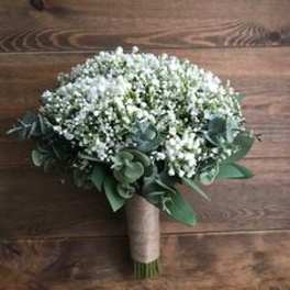 Round bouquet of tiny white flowers with green foliage and a wrapped handle