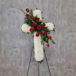 White floral cross with red roses on a stand