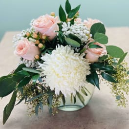 Pink roses and a white chrysanthemum in a glass vase