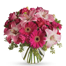 Pink lilies, gerbera daisies, roses, and carnations in a glass vase