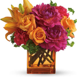 Orange and magenta flower arrangement in a square glass vase