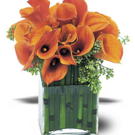 Orange calla lilies arranged in a square glass vase