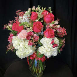 Pink roses and white hydrangeas in a glass vase with a ribbon