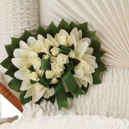 White floral spray with roses and lilies on a white casket