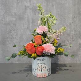 Pink and orange floral arrangement in a bear-printed ceramic container