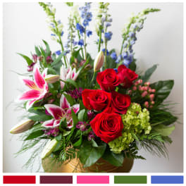 Bouquet of red roses, pink lilies, and blue delphinium in a gold vase