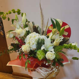 White floral arrangement with roses, lilies, and hydrangea in a red gift wrap